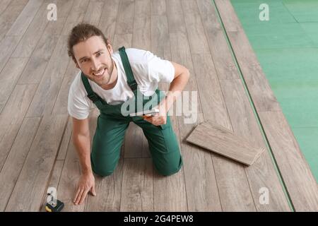 Carpenter installing laminate flooring in room Stock Photo