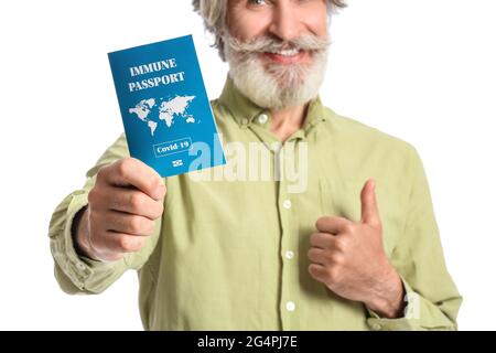 Senior man with immune passport showing thumb-up on white background Stock Photo