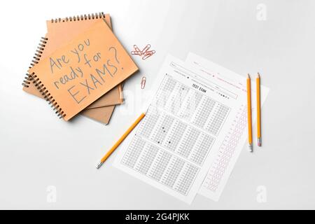 Stationery, answer sheets and notebook with text ARE YOU READY FOR EXAMS? on light background Stock Photo
