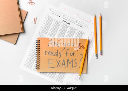Stationery, answer sheets and notebook with text ARE YOU READY FOR EXAMS? on light background Stock Photo