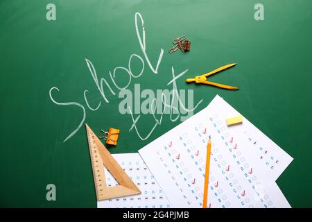 Answer sheets with stationery and text SCHOOL TEST on blackboard Stock Photo