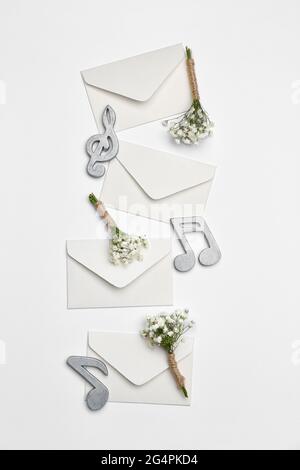 Beautiful gypsophila boutonnieres, envelopes and music notes on light background Stock Photo