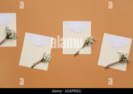 Beautiful gypsophila boutonnieres and wedding invitations on color background Stock Photo