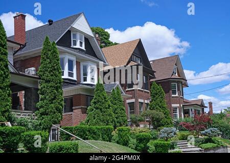 Residential street with row of older urban three story brick houses with rooms under the gables Stock Photo