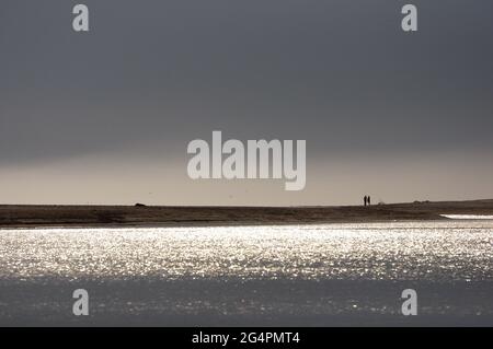 Couple walking on the beach during sunset near a river in Maldonado, Uruguay Stock Photo