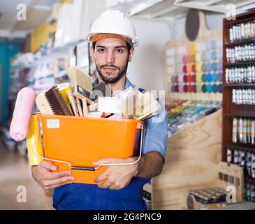 Active workman holding basket with picked tools Stock Photo
