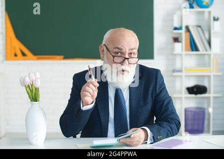 Teacher preparing for university exams. Professor holding a book and pointing. Teacher in college on university lecture. Stock Photo