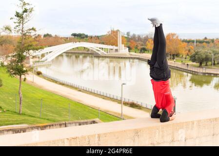 Man doing headstand exercise outdoors in a park Stock Photo