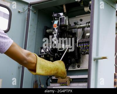 Men Gloves hand holding electric switch at supply unit room Stock Photo