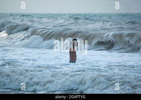 Palomino, Dibulla, La Guajira, Colombia - May 24 2021: Young Latin Man Entering Little by Little into the Deepest Waters of the Sea Waiting for the Wa Stock Photo