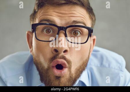 Closeup shocked funny male face portrait studio shot over grey background Stock Photo