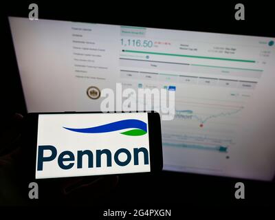 Person holding mobile phone with logo of British water utility company Pennon Group plc on screen in front of web page. Focus on phone display. Stock Photo