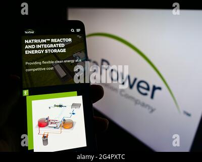 Person holding smartphone with webpage of US nuclear reactor company TerraPower LLC on screen in front of logo. Focus on center of phone display. Stock Photo