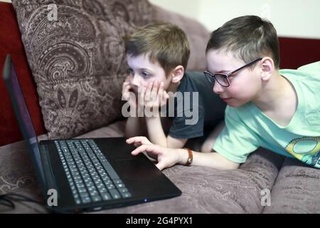 Two boys watching cartoon on laptop on sofa Stock Photo