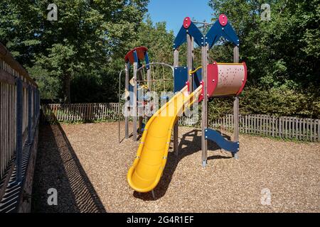 Climbing frame with yellow slide on a fenced playground Stock Photo