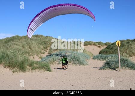 view of beach and sand dunes with Senior male paraglider in the distance, active seniors concept
