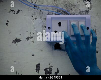 Blue hand due to electric shock concept presented on three pin holder. Stock Photo