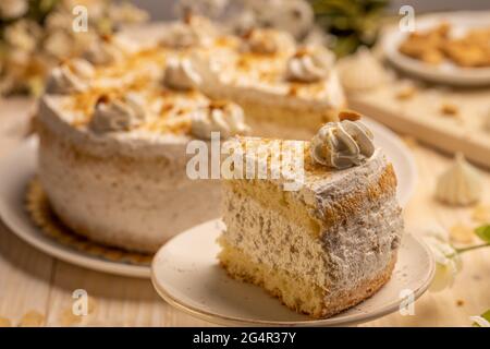 Vanilla cake with whipped cream and nuts, piece of cake on the plate Stock Photo