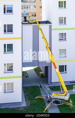 the specialist inspects the facade of the house with the help of a modern mobile self propelled hydraulic lifting platform Stock Photo