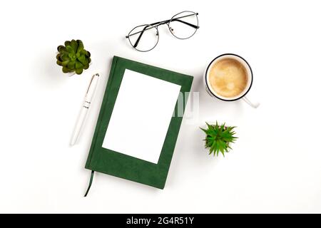 Light postcard mockup for design presentation on a white workplace with coffee, notebook, pen, glasses and potted flowers. Stock Photo