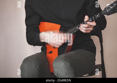 Man playing fast balalaika, close up photo with soft selective focus and motion blur effect. Russian folk music background Stock Photo