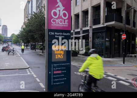 A cyclist rides past daily cycling statistics for the North-South CS6 Superhighway that allows commuters safe journeys south of Blackfriars Bridge, on 21st June 2021, in London, England. Stock Photo