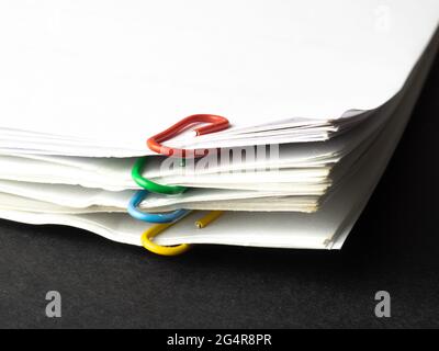Pile of paper sheets with multicolored paperclips Stock Photo