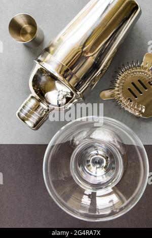 Top view of a bartender's metal shaker with a martini glass beside it on a gray background Stock Photo