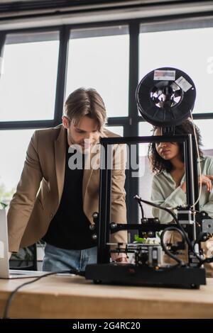 focused young interracial designers working with 3D printer in modern office Stock Photo