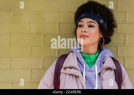 African american woman looking away near yellow brick wall Stock Photo