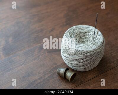 Cotton thread reel, needles and thimbles on the wooden surface. Needlework supplies Stock Photo