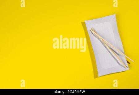 paper rectangular plates wooden chopsticks on yellow background, top view Stock Photo