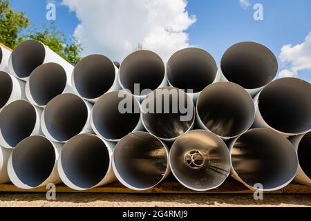 Downpipe warehouse. Steel pipes, parts for the construction of a roof drainage system in a warehouse. Stack of stainless steel pipes. Stock Photo