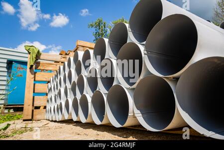 Downpipe warehouse. Steel pipes, parts for the construction of a roof drainage system in a warehouse. Stack of stainless steel pipes. Stock Photo