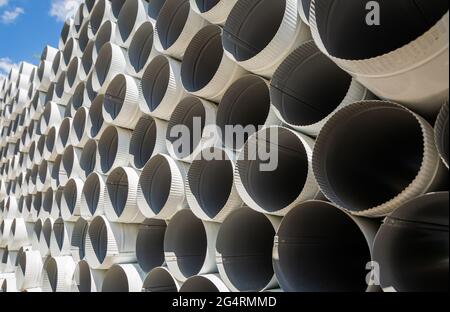 Downpipe warehouse. Steel pipes, parts for the construction of a roof drainage system in a warehouse. Stack of stainless steel pipes. Stock Photo