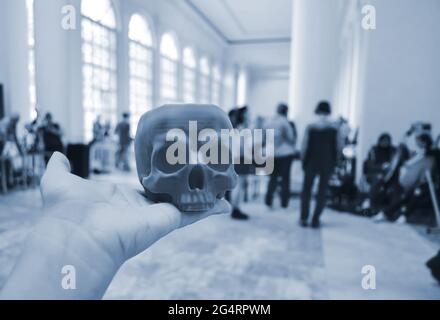 Skull printed on 3d printer in man's hand. On the back of a blurry plan - people Stock Photo