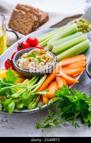 Platter of assorted fresh vegetables with avocado dip, hummus, marinated mushrooms and olives Stock Photo