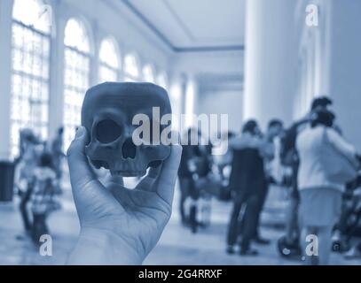 Skull printed on 3d printer in man's hand. On the back of a blurry plan - people Stock Photo