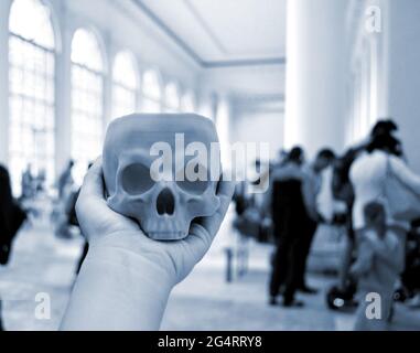Skull printed on 3d printer in man's hand. On the back of a blurry plan - people Stock Photo