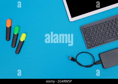 Office Workplace with Digital Gadgets Lying on Blue Table - Flat Lay Stock Photo