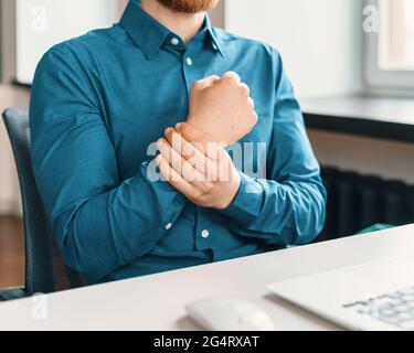Male office worker in blue suit suffering from wrist pain Stock Photo