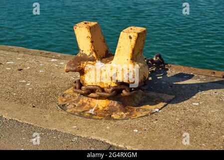 A twin horn mooring bollard with a heavy chain around it Stock Photo