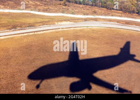 Airplane shadow on the land during the landing . Airplane flight in the sunny day . Silhouette of plane on the ground Stock Photo
