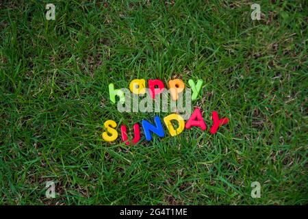 happy sunday lettering written with toy letters on the grass in the garden of the house Stock Photo