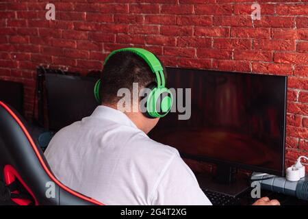 Guy in green headphones playing video games on the computer. Stock Photo
