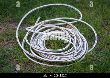 rolled up plastic garden irrigation hose on the grass. Stock Photo