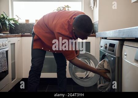 Young African man washing clothes in his kitchen Stock Photo