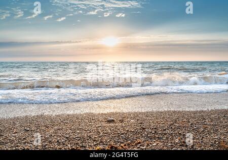 Green blue sea splashing waves backlit by setting sun in front of beautiful sunset sky background. Travel and tourism concept. Nature background. Grea Stock Photo