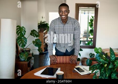 Smiling African businessman leaning on a table while working from home Stock Photo