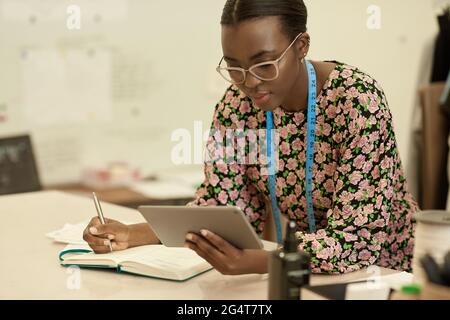African female clothes designer using a tablet in her studio Stock Photo